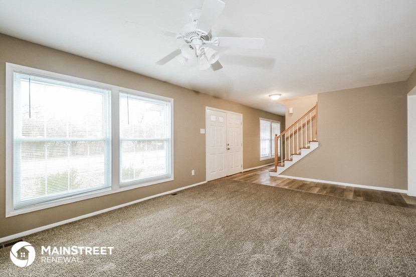 a living room with large windows and a ceiling fan
