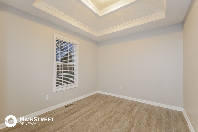 the upstairs bedroom with wood flooring and a window