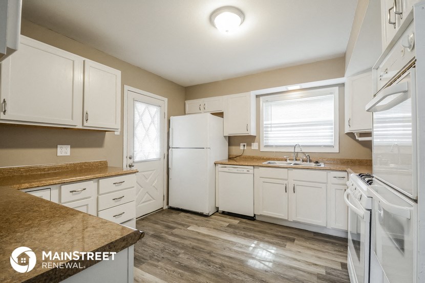a kitchen with white cabinets and white appliances and counter tops