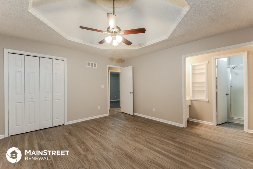 a living room with a ceiling fan and a door to a closet