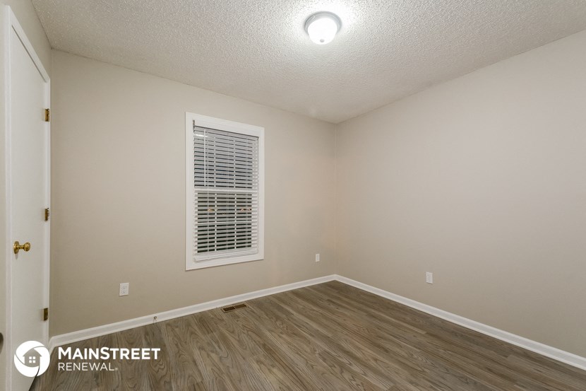 the interior of an empty room with wood flooring and a window