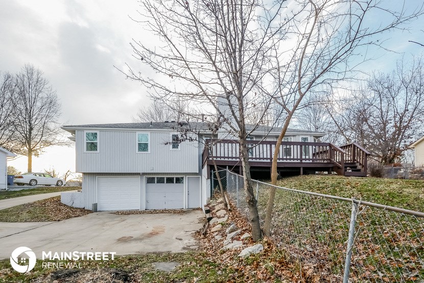 a white house with a deck on top of a hill