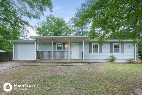 a small white house with a porch and some trees
