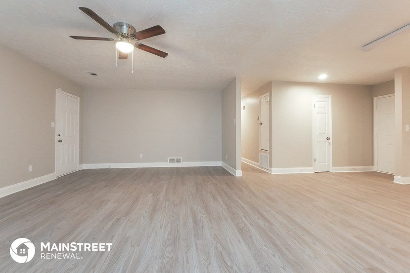 an empty living room with wood flooring and a ceiling fan