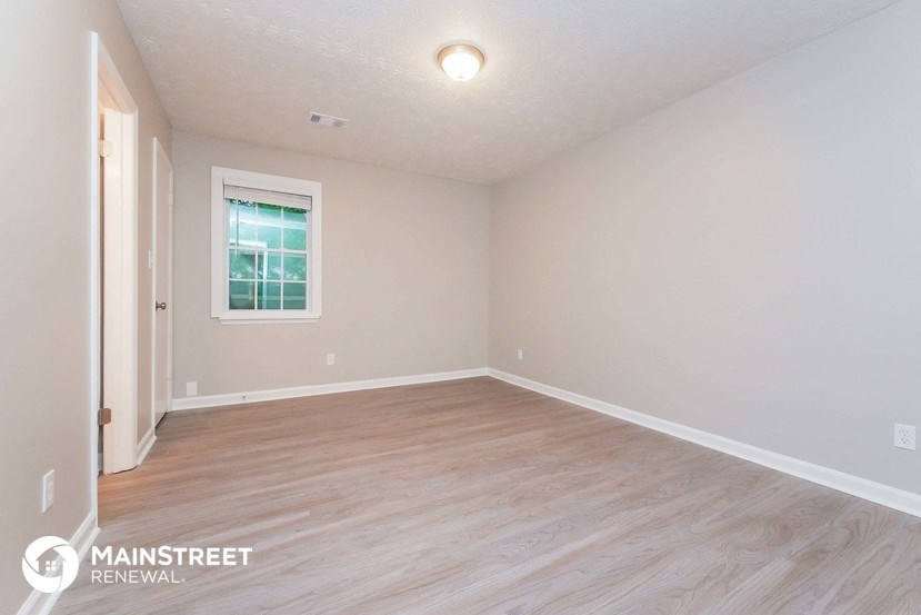 an empty living room with wood flooring and a window