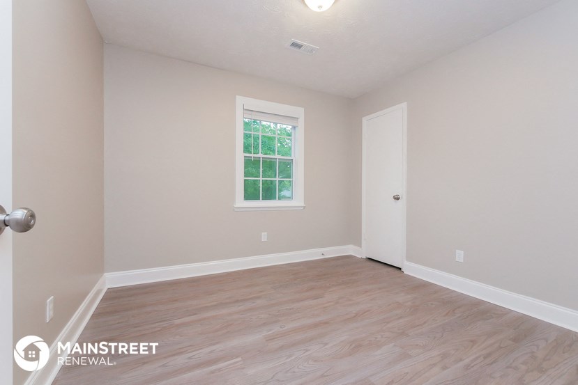 the living room of a home with wood flooring and a window