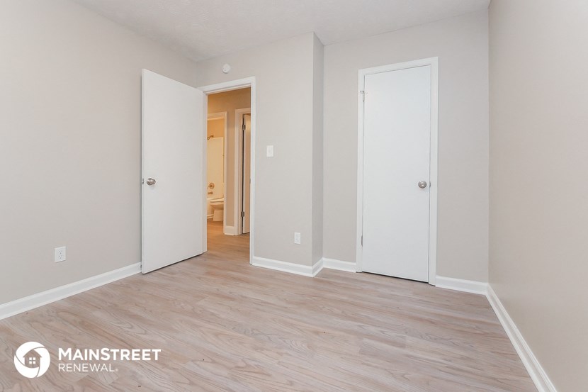 the living room of an apartment with a wood floor and white doors