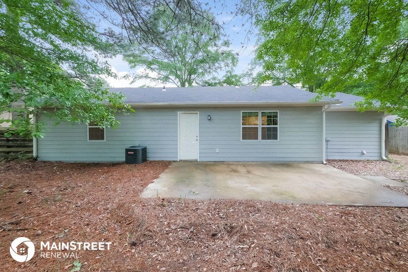 a small blue house with a driveway and trees