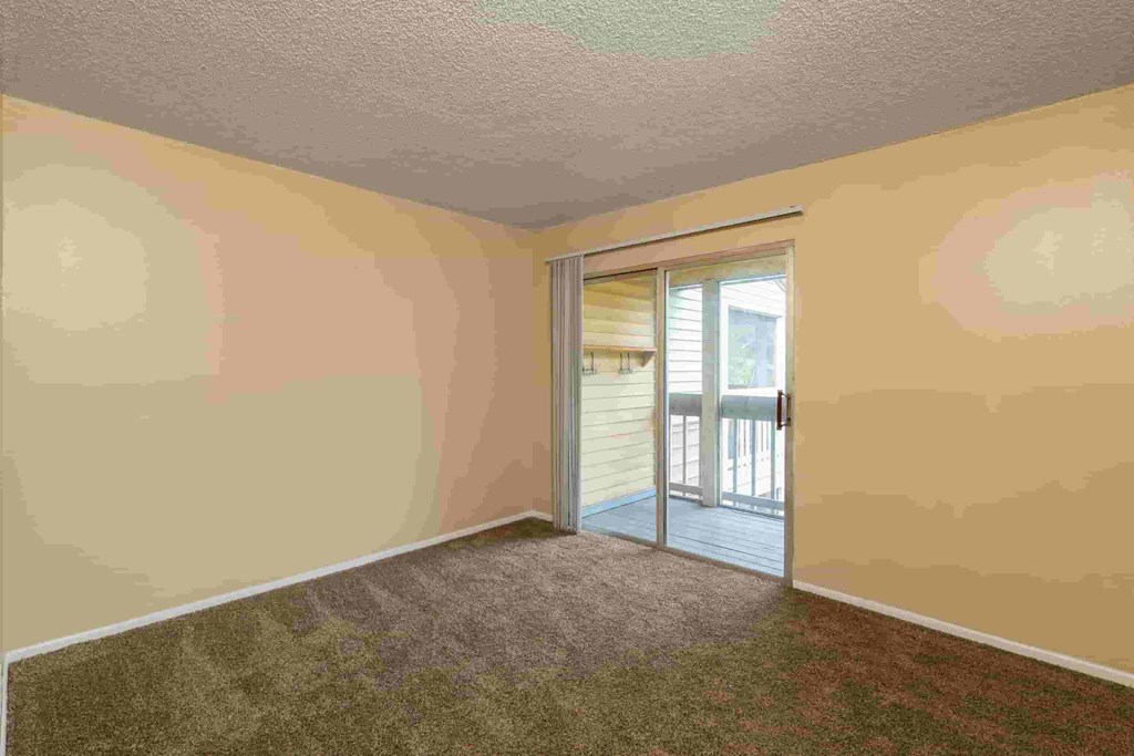 an empty room with a door to a balcony