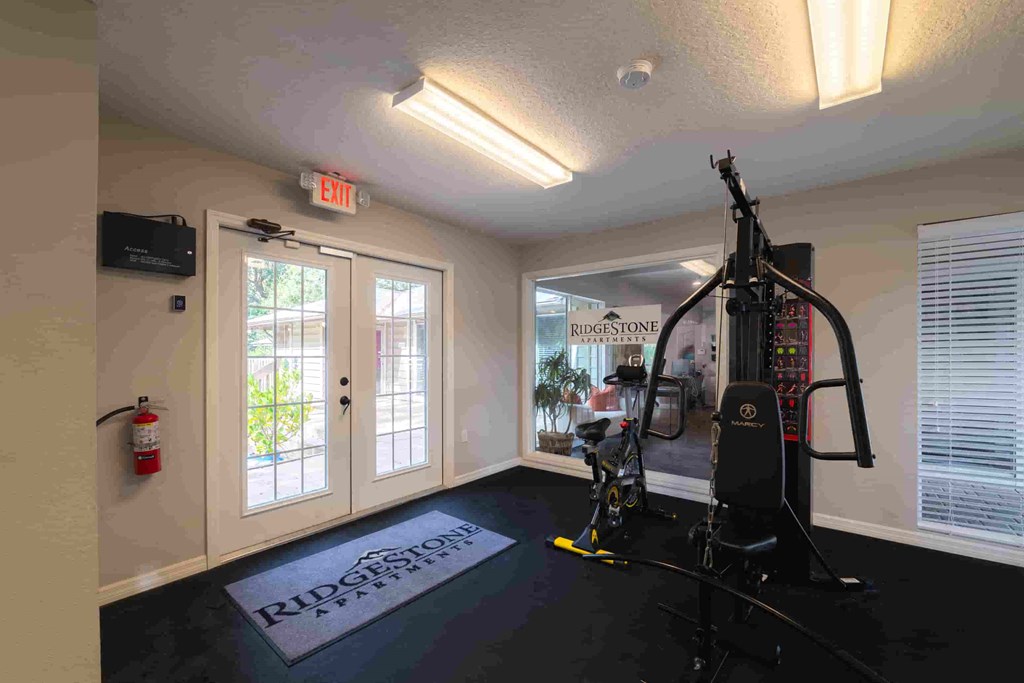 a home gym with a treadmill and a door to a patio