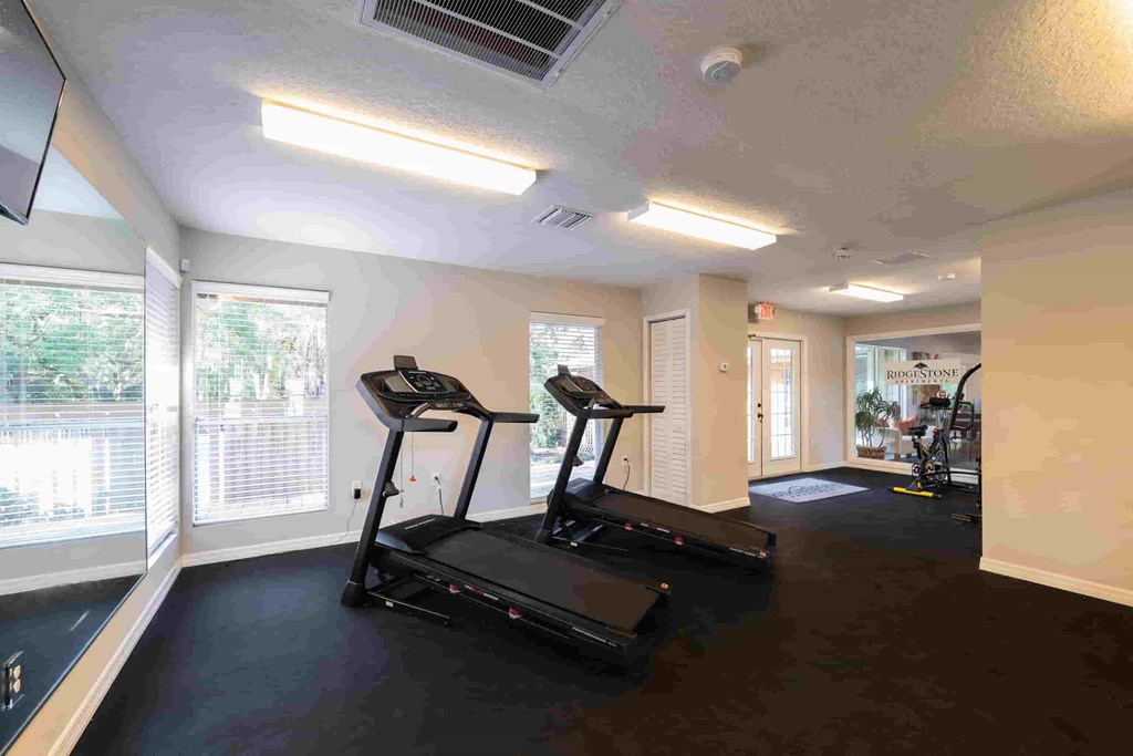 a workout room with treadmills and windows in a building