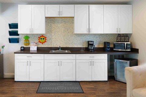 A kitchen with white cabinets and a black countertop.