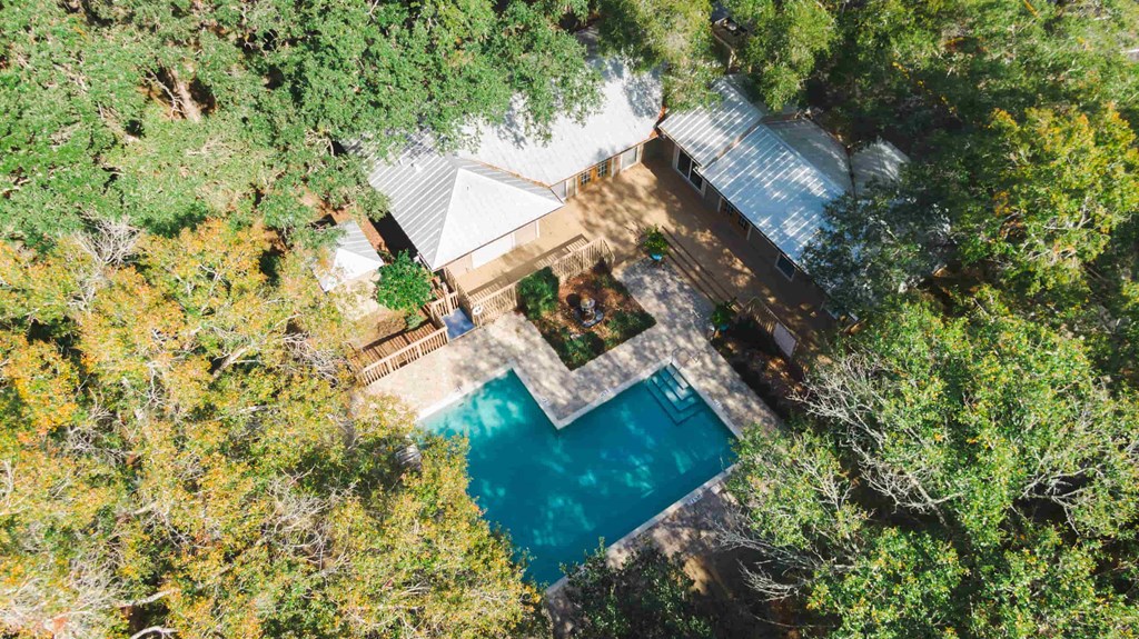 an overhead view of a pool and backyard with trees