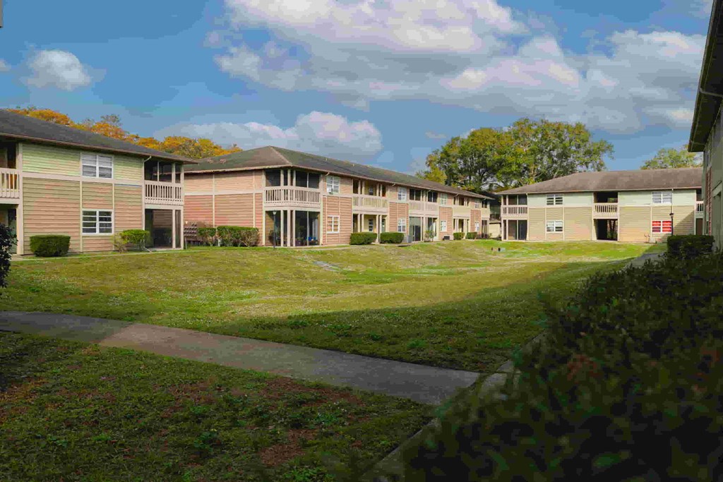 an exterior view of a row of apartment buildings on a green lawn