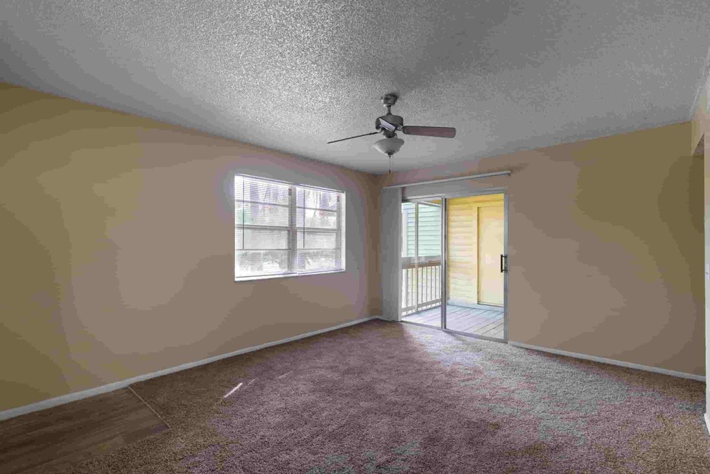 an empty living room with a ceiling fan