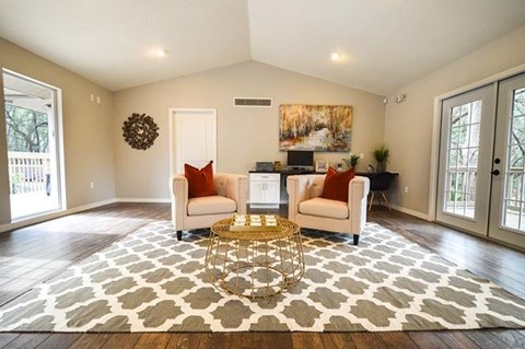 A living room with a large rug and two chairs.