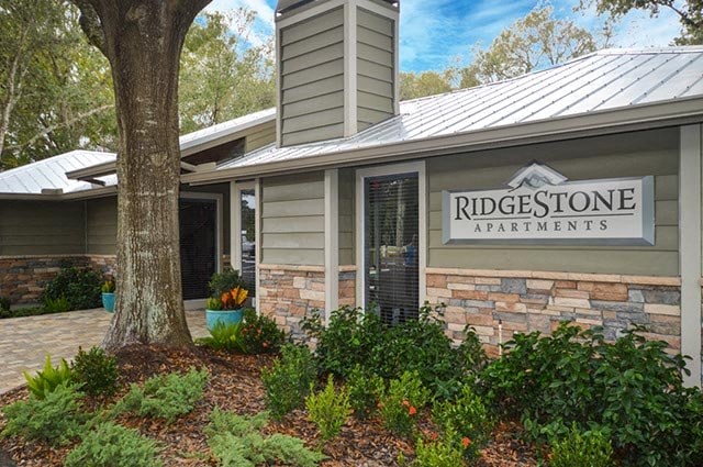 the front of the ridgestone apartments building with a tree