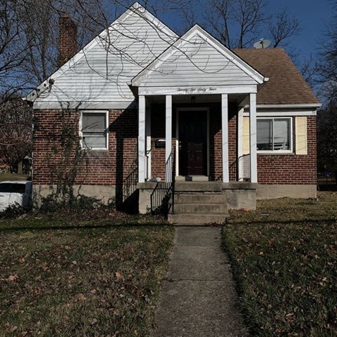 a small brick house with a sidewalk in front of it