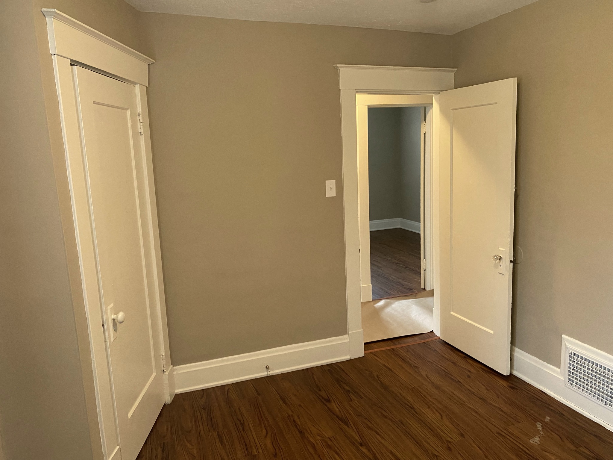 a bedroom with two doors and a hallway with a door to a closet and a