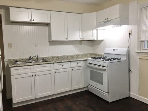 a white kitchen with a stove and a sink