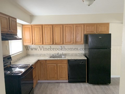 A kitchen with black appliances and wooden cabinets.