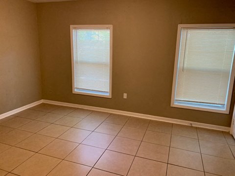 a living room with a tiled floor and two windows