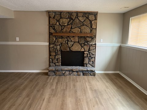 a living room with a stone fireplace and a wooden floor