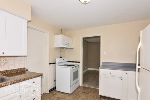 A kitchen with white cabinets and appliances.