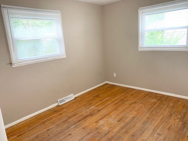 an empty room with a wooden floor and two windows
