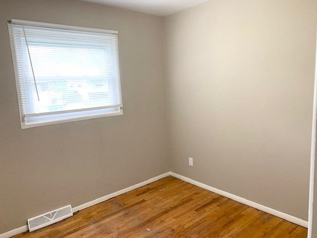 an empty room with a window and a wooden floor