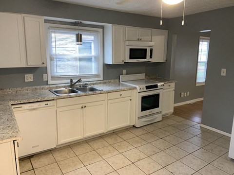 A kitchen with white cabinets and a granite countertop.