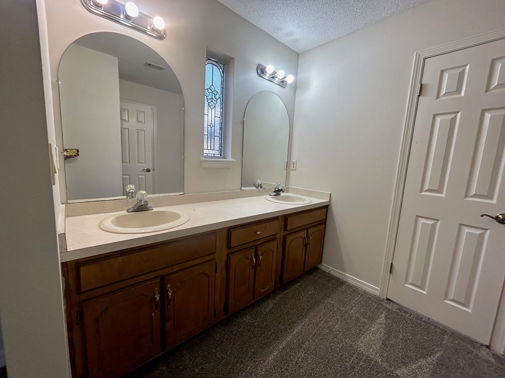 A bathroom with a sink, mirror, and lighting fixtures.