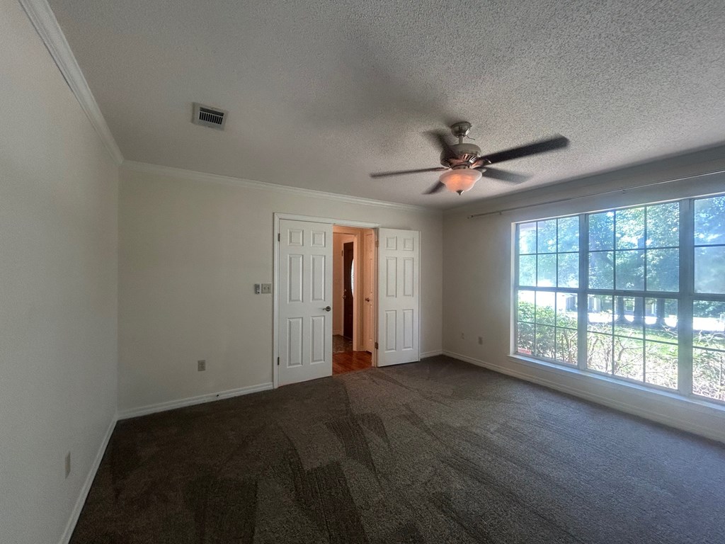 A room with a ceiling fan and carpeted floor.