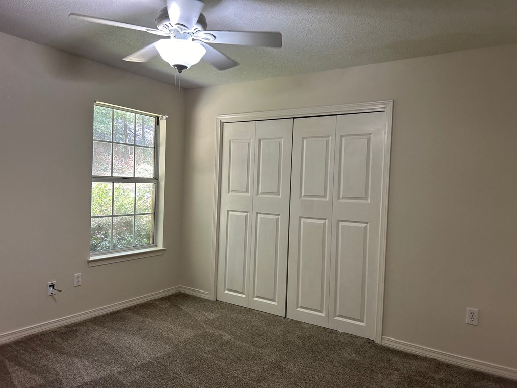 A room with a ceiling fan and a window.