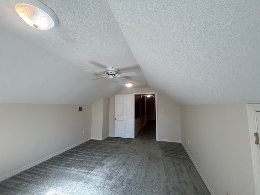 A room with a ceiling fan and carpeted floor.