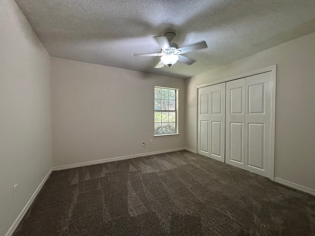 A room with a ceiling fan and a window with blinds.