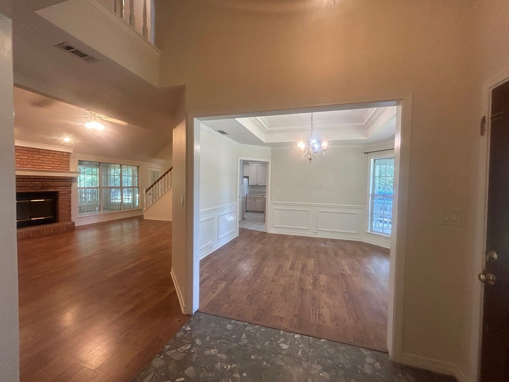 A large open room with wooden floors and a stone floor leading to a hallway.