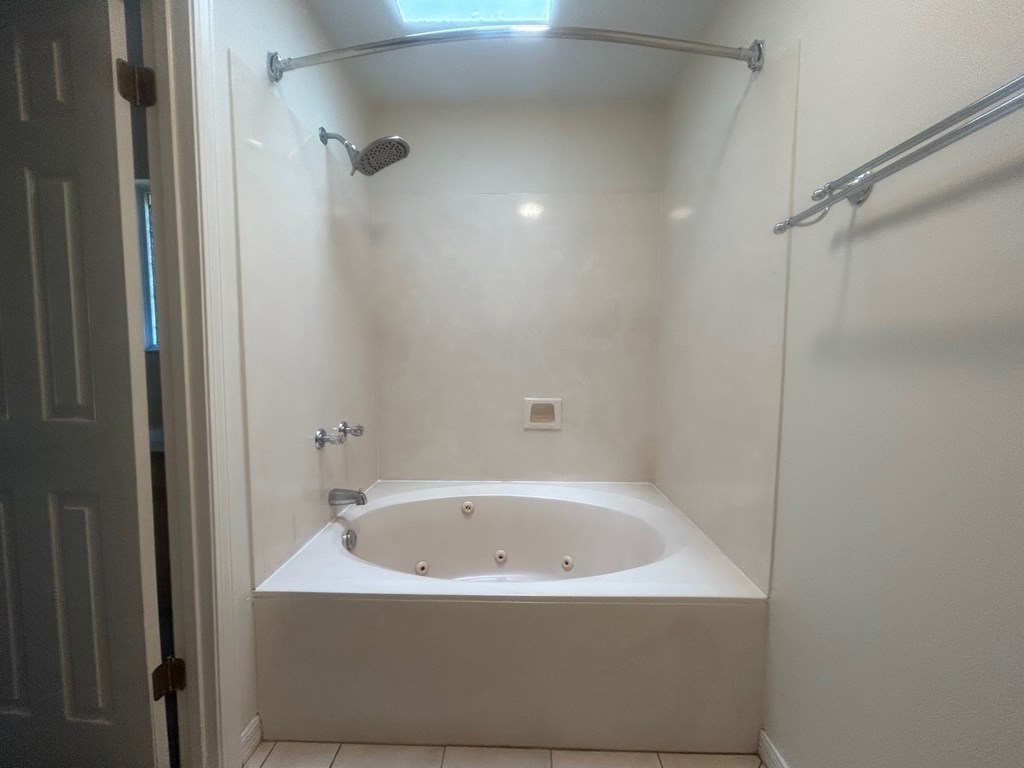 A white bathtub with a shower head and a shower curtain rod.