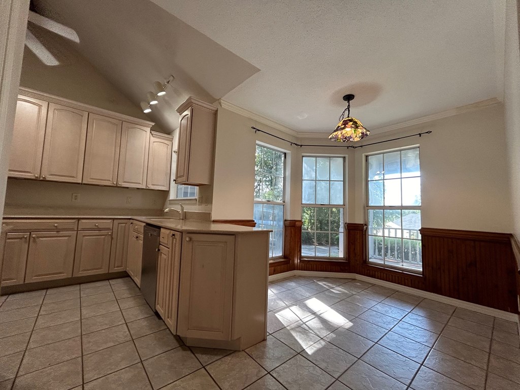 A kitchen with beige cabinets and a tile floor.