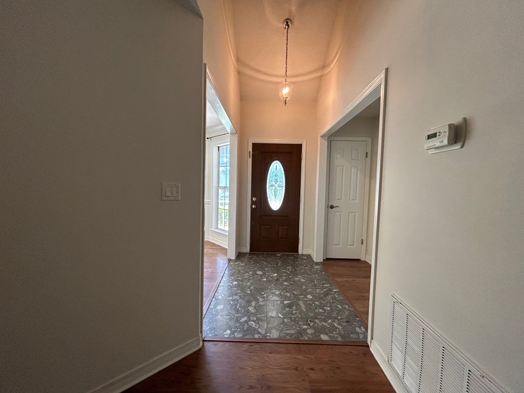 A hallway with a wooden door and a patterned rug.