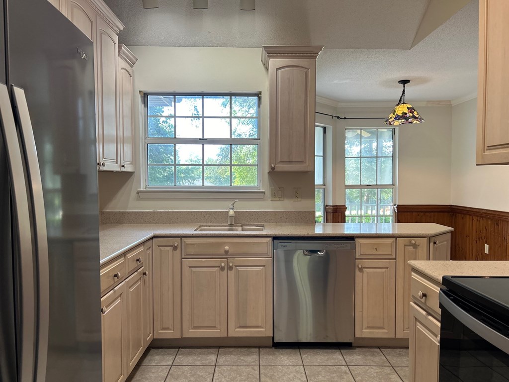 A kitchen with wooden cabinets and a stainless steel refrigerator.