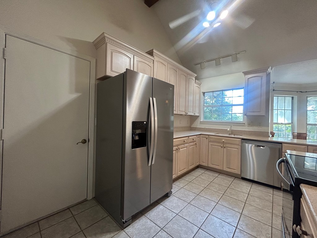 A kitchen with a refrigerator and a stainless steel dishwasher.