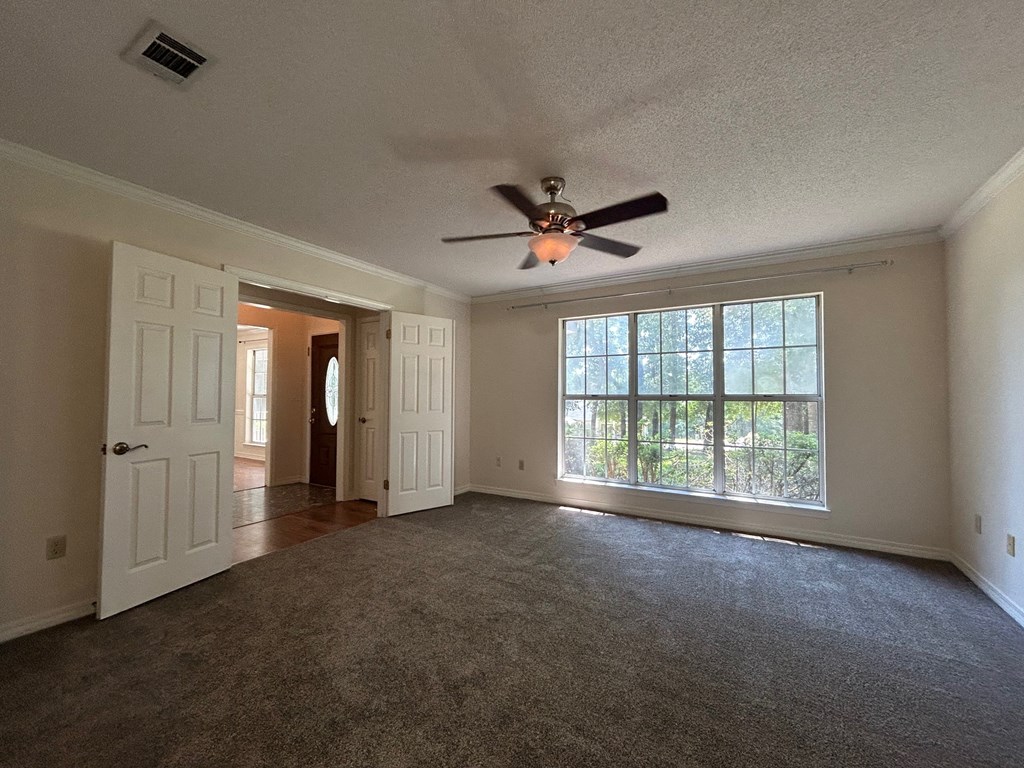 A room with a ceiling fan and a large window.