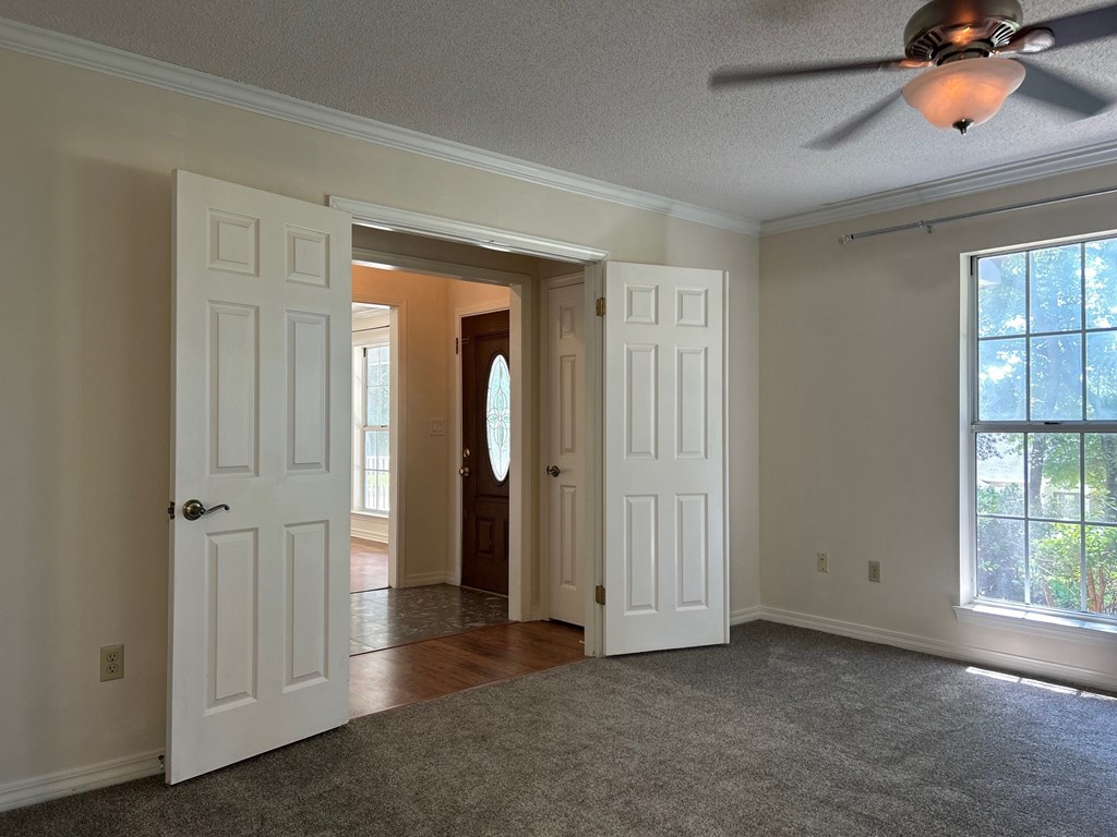 A room with a ceiling fan and a window with a view of trees.