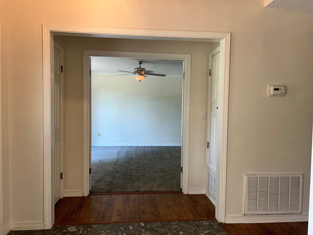 A room with a ceiling fan and a door leading to a hallway.