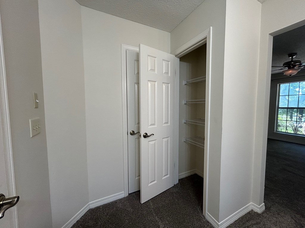 A white door is open to a room with a ceiling fan.