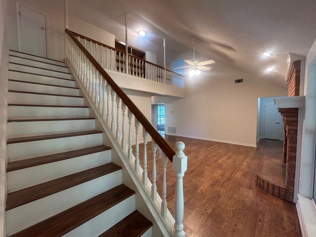 A staircase with white railings and wooden steps leads to a room with a ceiling fan.