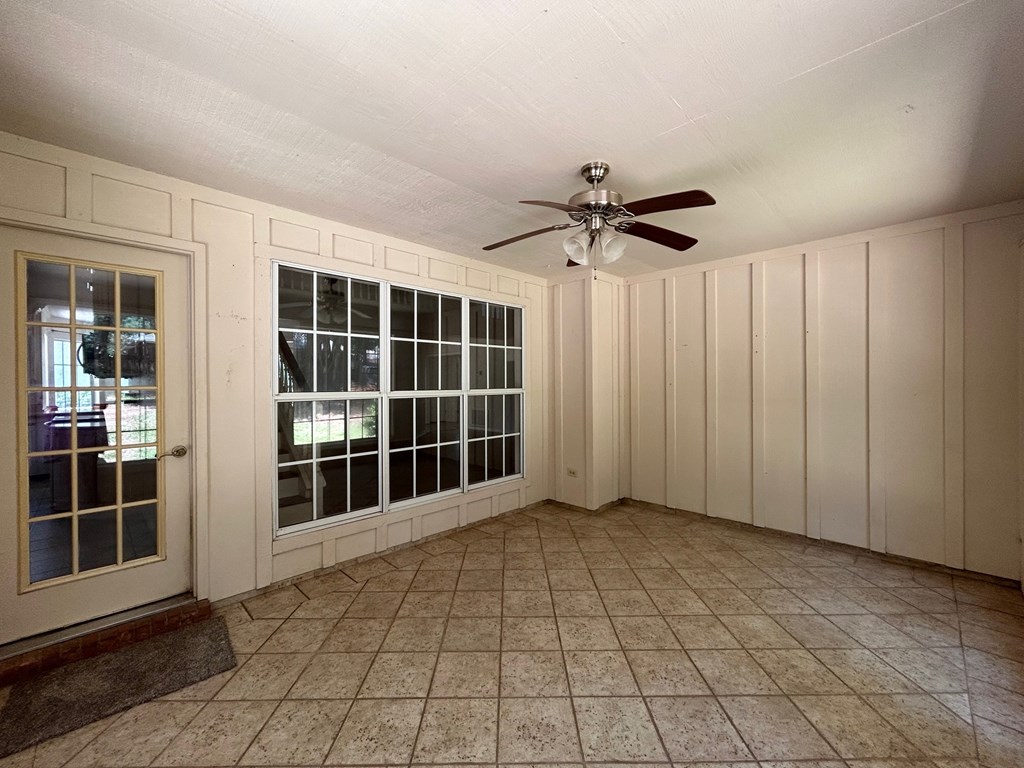 A room with a ceiling fan and tiled flooring.
