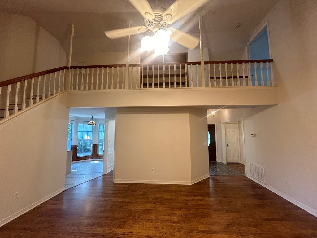 A room with a ceiling fan and wooden floors.
