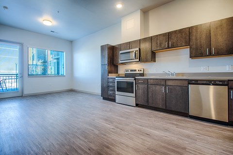 an empty kitchen with stainless steel appliances and wooden cabinets